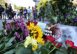 Poster with a portrait of Pavel Sheremet and the inscription "Who killed Paul?" And flowers