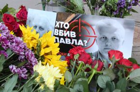 Poster with a portrait of Pavel Sheremet and the inscription "Who killed Paul?" And flowers
