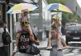 A man with a woman carry on their shoulders children with umbrellas
