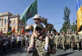 A boy on the shoulders of a military man