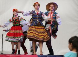 Участники фестиваля в этнических костюмах танцуют