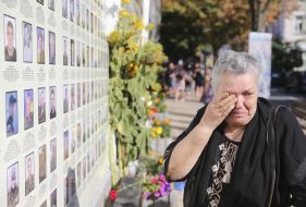 Жінка біля меморіалу «Стіна народної пам’яті»