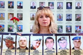 Woman holds photos of fallen soldiers