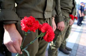 Военнослужащие держат красные гвоздики