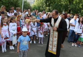 Священник окропляет святой водой школьника