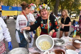 Woman in Ukrainian national costume offers dumplings in a bowl