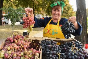 Woman in embroidery offers grapes
