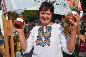 Woman in embroidery offers canning in glass jars