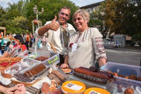 Man and woman in embroideries offer meat products