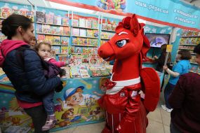 Аниматор в костюме лошади у стенда с детской литературой