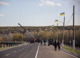 Автомобиль с подъемным механизмом поднимает бревна с обочины дороги