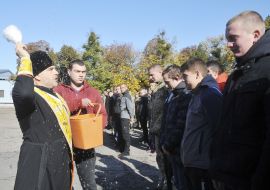 Священник окропляет святой водой призывников