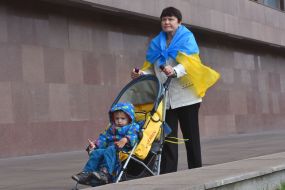 Женщина с флагом Украины везет коляску с ребенком