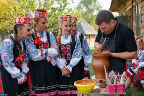 Девушки в гуцульских народных костюмах наблюдают за работой гончара