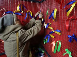 A woman ties a yellow-blue ribbon on a net
