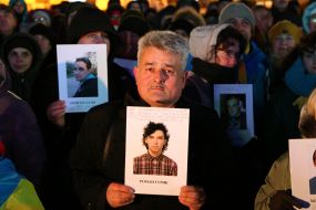 Participant Vic "We Have Dignity!" holds a portrait of Heavenly Hundred Hero Roman Roman Gurick