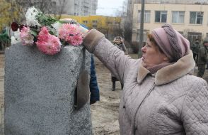 Женщина кладет цветы к Памятному знаку в честь защитников Украины