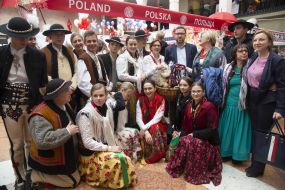 Participants of the fair in national costumes near the counter from the Polish Embassy