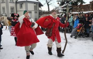 Святий Миколай з помічником несуть мішки з подарунками
