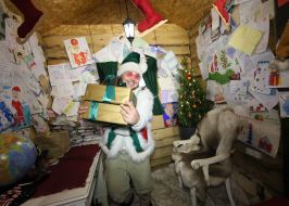 Помічник Святого Миколая тримає коробки з подарунками