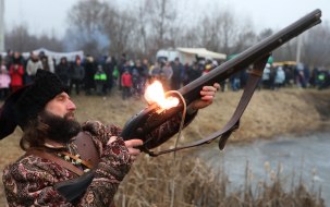 Reconstruction participant in a historical costume shoots from a musket