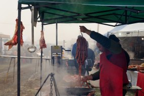 Участник фестиваля мясников готовит к копчению колбаски