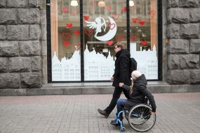 Girl in a wheelchair with her husband near a valentine's storefront "Zum" decorated for Valentine's Day