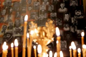 Candles on the background of a poster with photos of Heroes of Heavenly Hundred