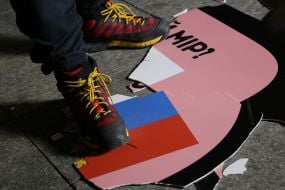 Плакат с изображением российского флага под ногами участника акции