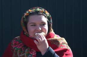 Girl in traditional headscarf and wreath eating dumplings