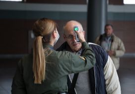 An airport employee checks the temperature of the passenger's body