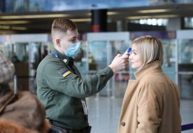 Сотрудник аэропорта проверяет температуру тела пассажира