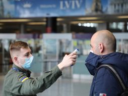 An airport employee checks the temperature of the passenger's body