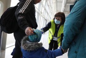 An airport employee checks the temperature of the passenger's body