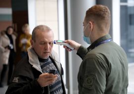 An airport employee checks the temperature of the passenger's body