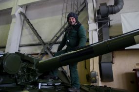 Работник завода залезает в кабину танка