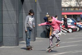 A boy in a medical mask rides a skateboard