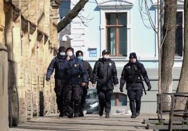 Law enforcement officers in medical masks patrol the street