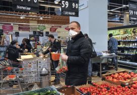 A man in a medical mask chooses goods in a supermarket
