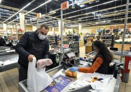 A man in a medical mask is paid at the checkout for supermarket goods