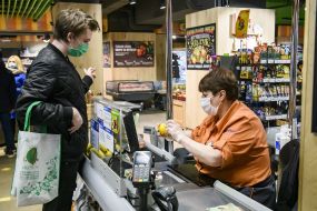 The buyer in the medical mask is paid at the checkout for the goods in the supermarket