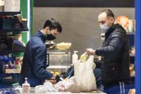 A man in a medical mask is paid at the checkout for supermarket goods