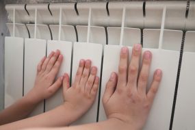 Детские руки измеряют температуру батареи