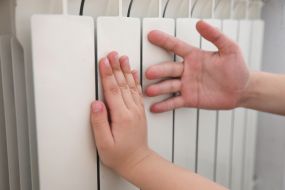 Детские руки измеряют температуру батареи