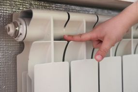 Детские руки измеряют температуру батареи