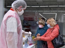 Buyers in masks disinfect their hands at the Auchan hypermarket in Zaporozhye