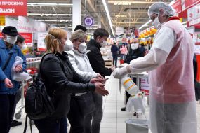 Buyers in masks disinfect their hands at the Auchan hypermarket in Zaporozhye