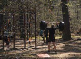 Мужчина поднимает штангу на спортивной площадке в парке