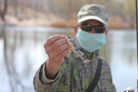 A fisherman in a medical mask with a fishing rod