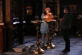 The parishioner puts candles on the candlestick in the Vladimir Cathedral